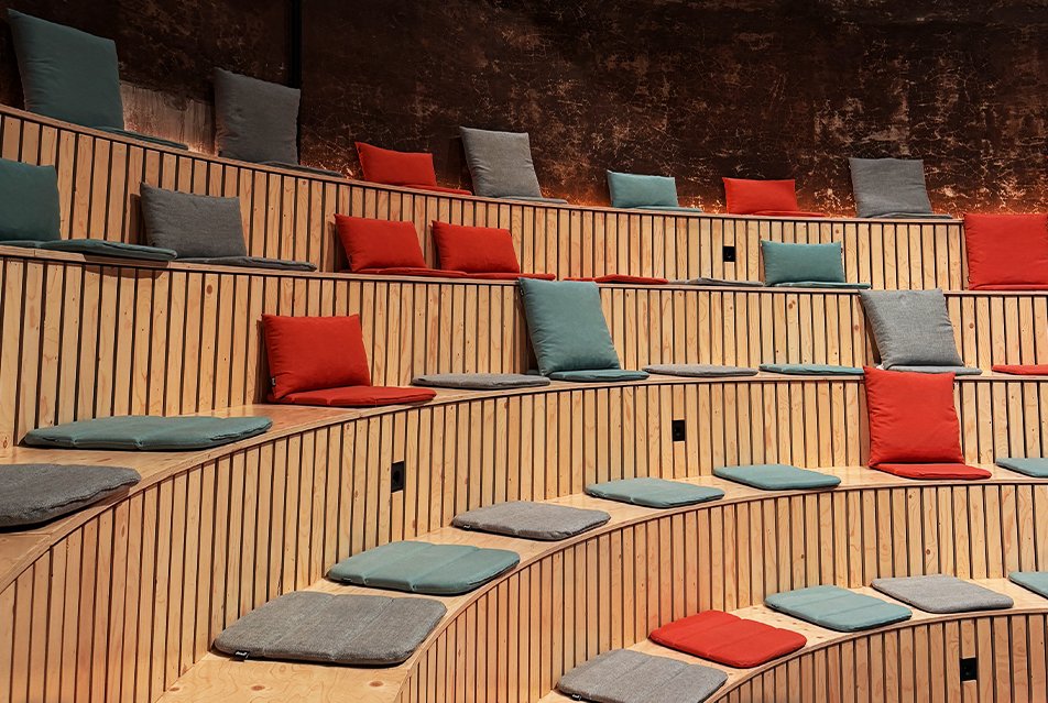 Theater zaal met rode, grijze en blauwe kussentjes.